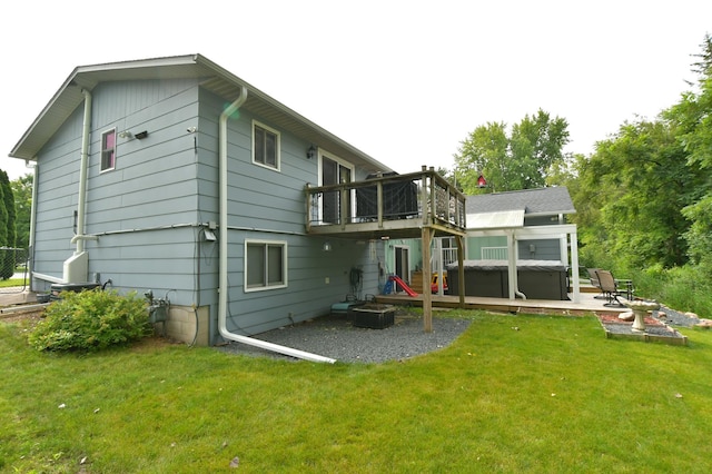 back of house with a wooden deck, a hot tub, a patio area, and a lawn