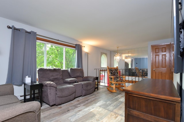 living room featuring an inviting chandelier, baseboard heating, and light wood-type flooring