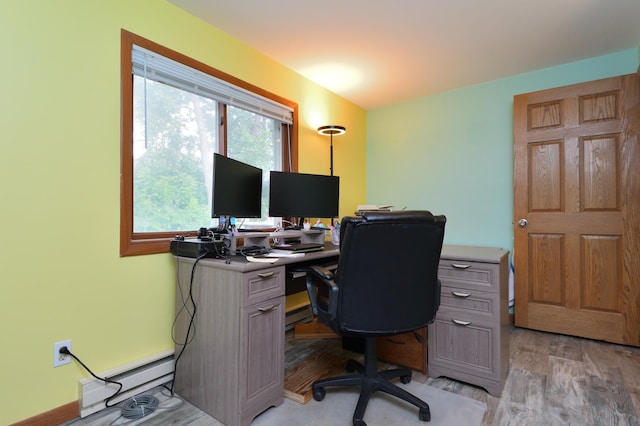 home office with a baseboard heating unit and light hardwood / wood-style flooring