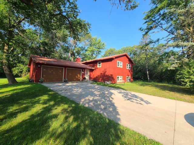 split level home featuring a garage, an outbuilding, and a front yard