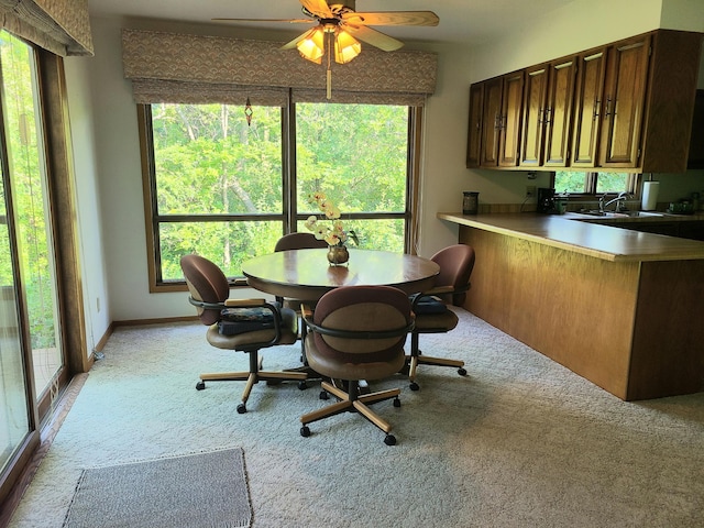 carpeted dining space featuring a healthy amount of sunlight, sink, and ceiling fan