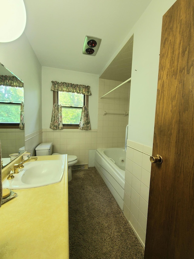 full bathroom with vanity, toilet, tiled shower / bath combo, and tile walls