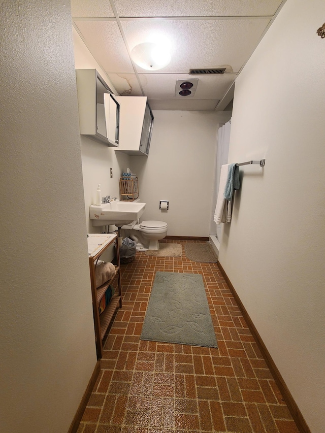 bathroom with sink, a paneled ceiling, and toilet