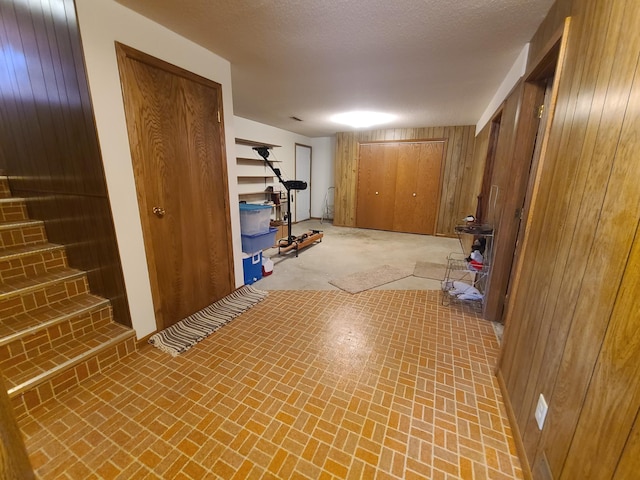 basement featuring a textured ceiling and wood walls