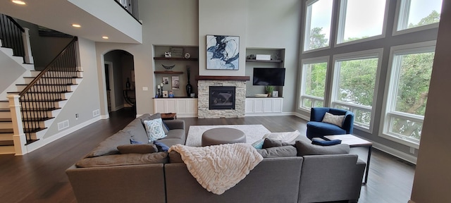 living room with a stone fireplace, plenty of natural light, and a towering ceiling