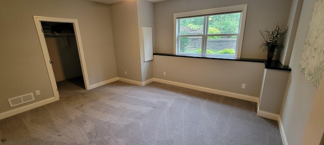 unfurnished bedroom featuring a spacious closet, a closet, and light colored carpet