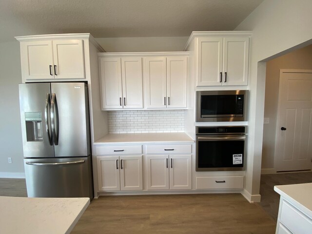 kitchen with white cabinets, light hardwood / wood-style flooring, appliances with stainless steel finishes, and decorative backsplash