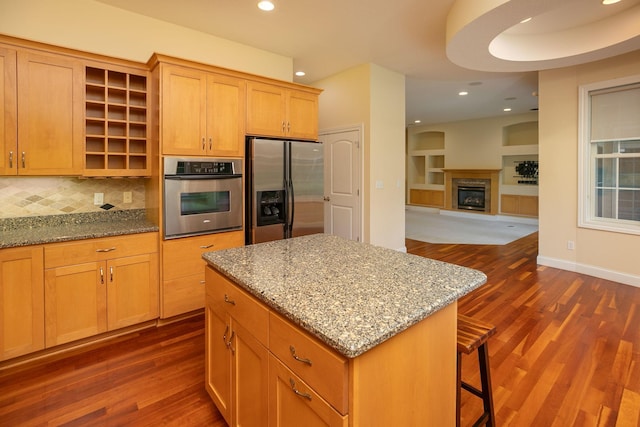 kitchen featuring stainless steel appliances, light stone counters, a center island, and dark hardwood / wood-style floors