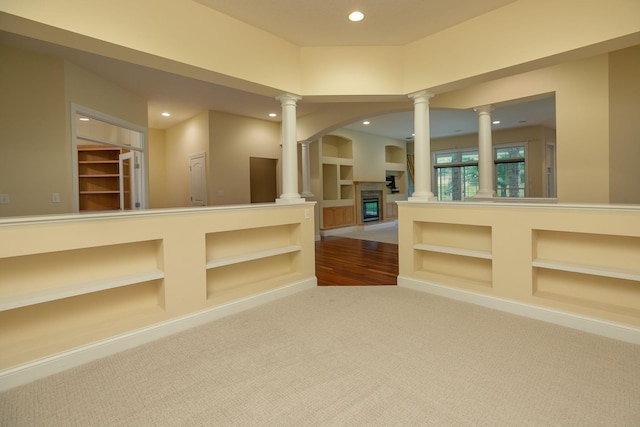 carpeted empty room with built in shelves and ornate columns