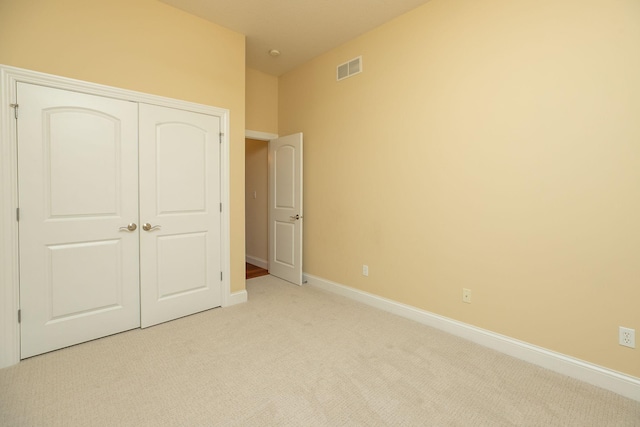 unfurnished bedroom with light carpet and a closet