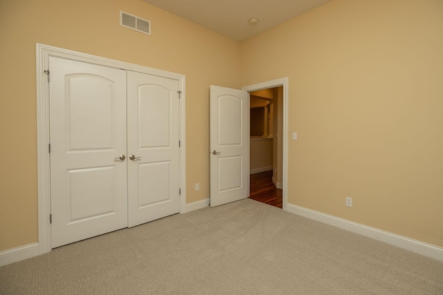 unfurnished bedroom with light carpet and a closet