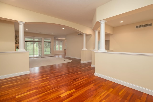 unfurnished living room featuring ornate columns and hardwood / wood-style flooring