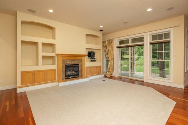 unfurnished living room featuring dark hardwood / wood-style floors and built in features