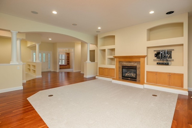 unfurnished living room featuring decorative columns, dark hardwood / wood-style floors, and built in features