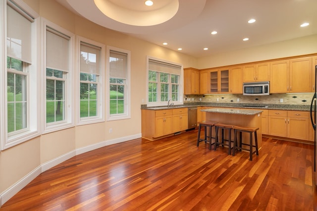 kitchen featuring tasteful backsplash, a center island, appliances with stainless steel finishes, a breakfast bar, and dark hardwood / wood-style flooring