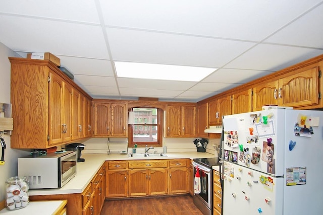 kitchen featuring dark wood-type flooring, a paneled ceiling, appliances with stainless steel finishes, and sink