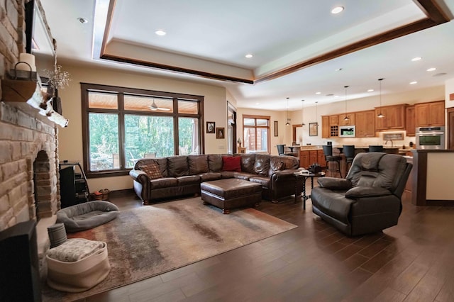 living room with a fireplace, dark hardwood / wood-style flooring, and a raised ceiling