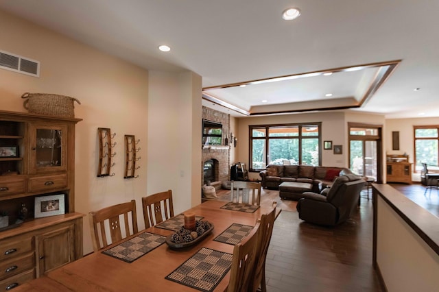 dining room featuring dark hardwood / wood-style floors, a fireplace, and a tray ceiling