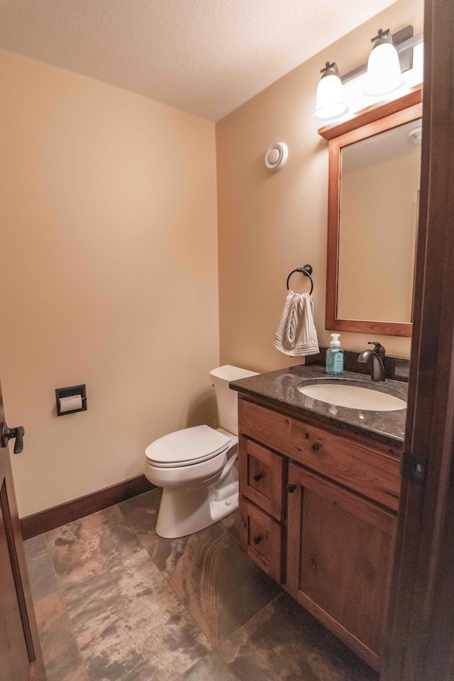 bathroom with a textured ceiling, vanity, and toilet