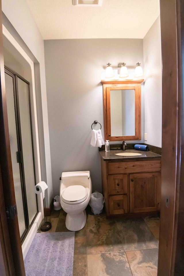 bathroom featuring vanity, toilet, and a shower with shower door