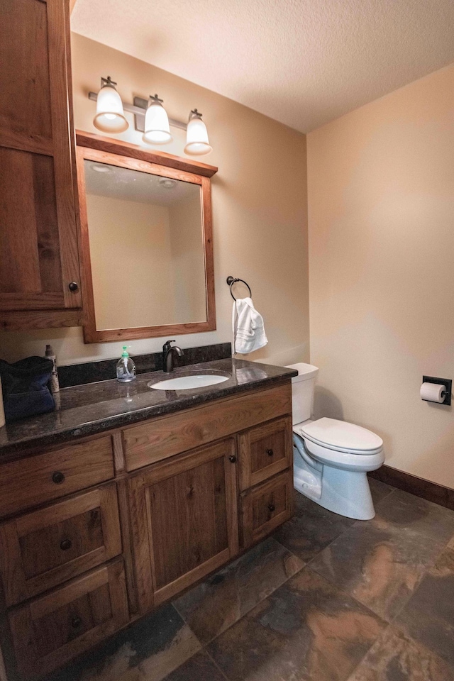 bathroom with vanity, toilet, and a textured ceiling