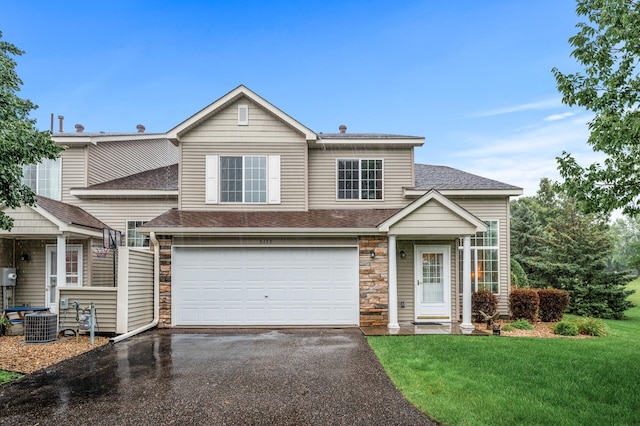 view of front of house featuring cooling unit, a front yard, and a garage