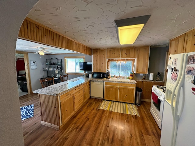 kitchen featuring white appliances, sink, ceiling fan, dark hardwood / wood-style floors, and kitchen peninsula