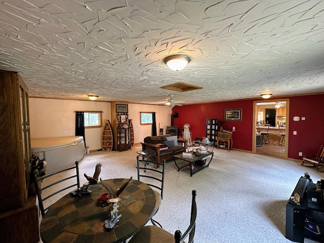 carpeted living room featuring a wood stove and a textured ceiling