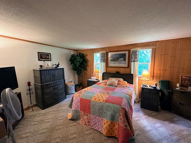 bedroom with carpet, ornamental molding, a textured ceiling, and wooden walls