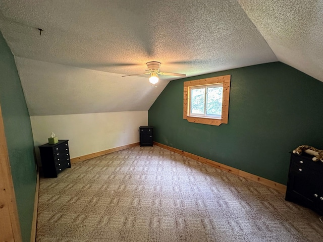 bonus room with ceiling fan, vaulted ceiling, a textured ceiling, and carpet