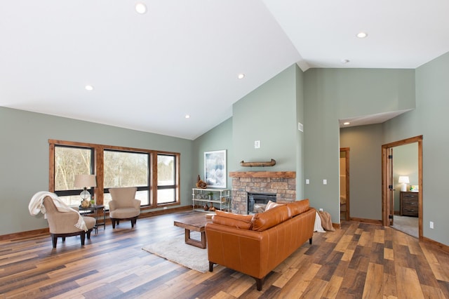 living room with hardwood / wood-style flooring, a stone fireplace, and high vaulted ceiling