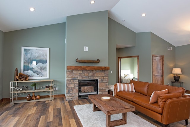 living room with hardwood / wood-style floors, high vaulted ceiling, and a stone fireplace