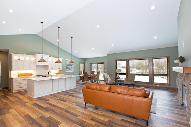 living room featuring dark hardwood / wood-style floors, sink, a fireplace, and high vaulted ceiling