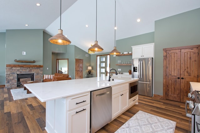 kitchen with white cabinets, decorative light fixtures, stainless steel appliances, and a large island with sink