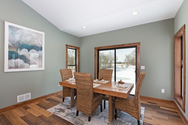 dining space with wood-type flooring and vaulted ceiling