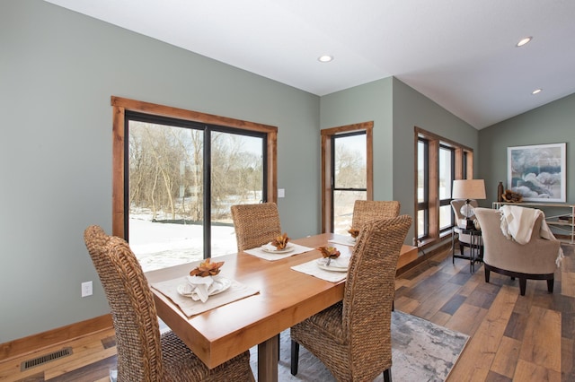 dining space featuring dark wood-type flooring and vaulted ceiling