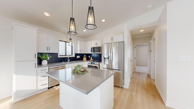 kitchen featuring appliances with stainless steel finishes, decorative light fixtures, white cabinets, a kitchen island, and lofted ceiling