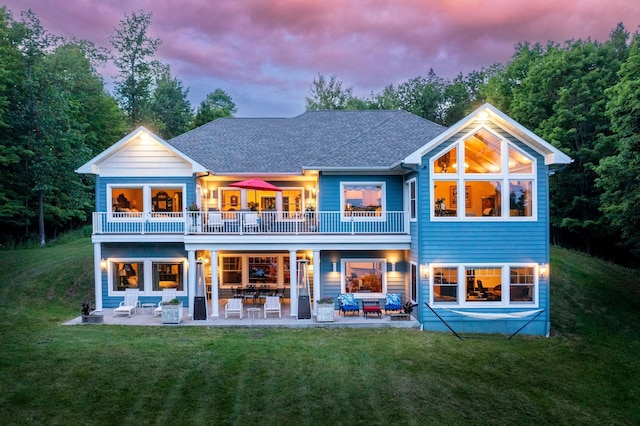 rear view of house with a patio, a balcony, outdoor lounge area, roof with shingles, and a lawn