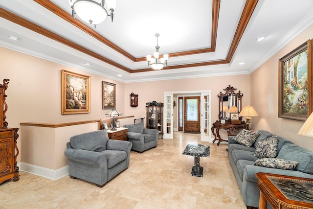 living area featuring ornamental molding, a tray ceiling, baseboards, and an inviting chandelier