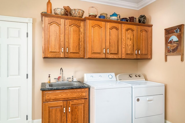 washroom with cabinet space, crown molding, separate washer and dryer, and a sink