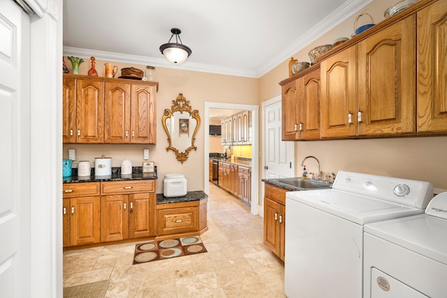 clothes washing area featuring cabinet space, washing machine and dryer, crown molding, and a sink