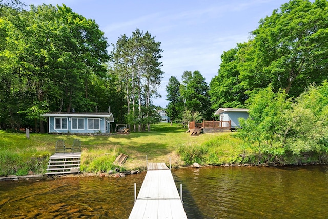 dock area featuring a deck with water view and a lawn