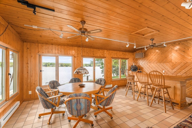 dining area with wood walls, a baseboard heating unit, and a wealth of natural light