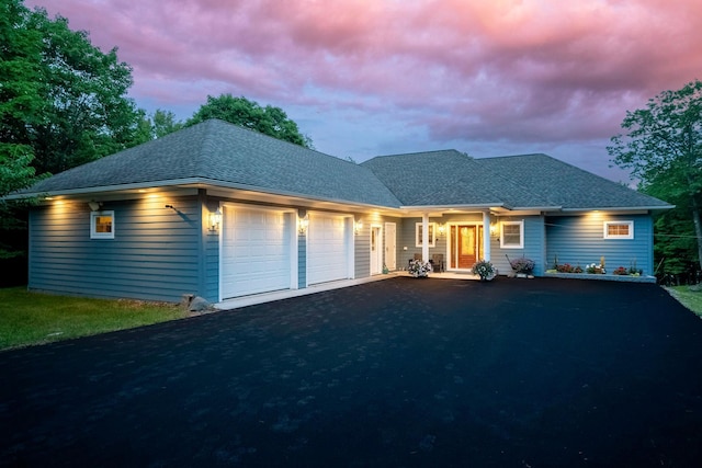 ranch-style home with aphalt driveway, roof with shingles, and an attached garage