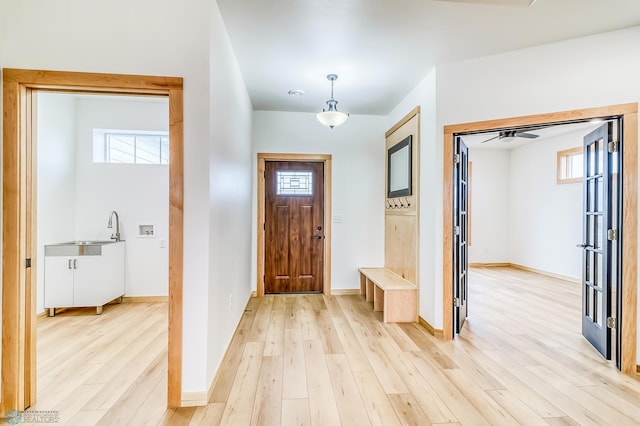 foyer with ceiling fan, sink, and light wood-type flooring