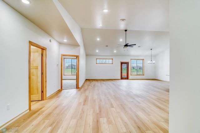 empty room with ceiling fan with notable chandelier and light hardwood / wood-style flooring