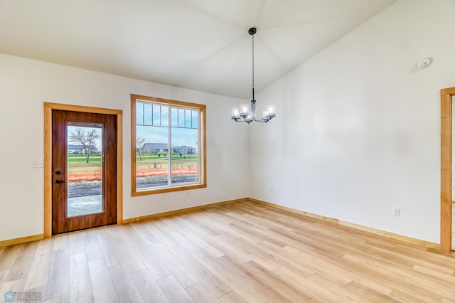 unfurnished dining area featuring an inviting chandelier, vaulted ceiling, and light wood-type flooring