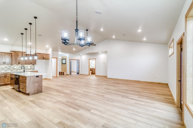 kitchen featuring a center island with sink, pendant lighting, vaulted ceiling, and light wood-type flooring