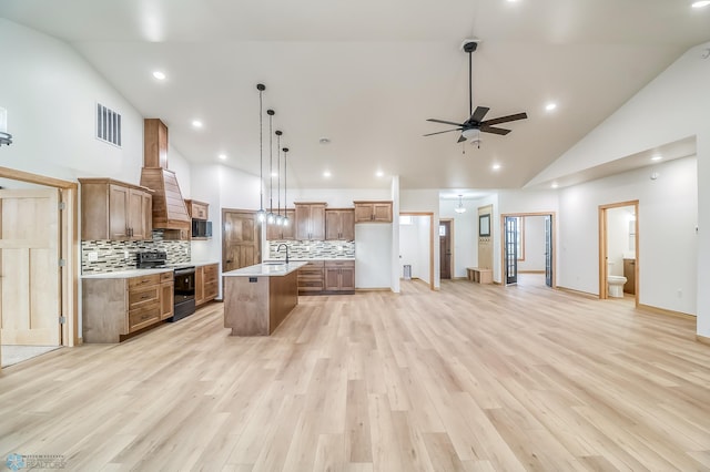 kitchen featuring ceiling fan, a center island, black appliances, and light wood-type flooring