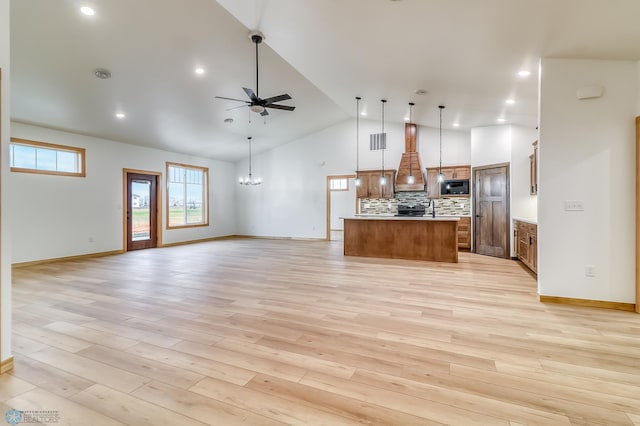 kitchen featuring ceiling fan with notable chandelier, a center island, light wood-type flooring, and hanging light fixtures